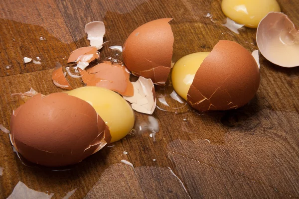 Huevos rotos en el suelo de madera — Foto de Stock