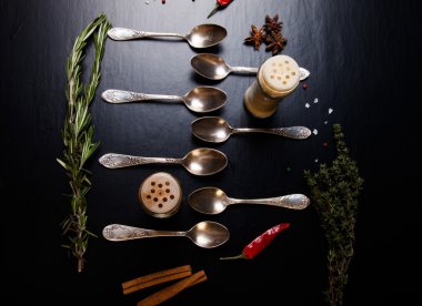 Otlar ve baharatlar ile siyah bir zemin üzerine eski metal kaşık