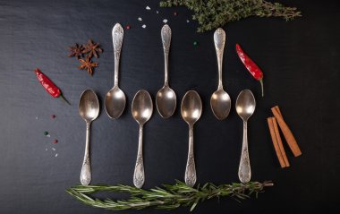 Otlar ve baharatlar ile siyah bir zemin üzerine eski metal kaşık