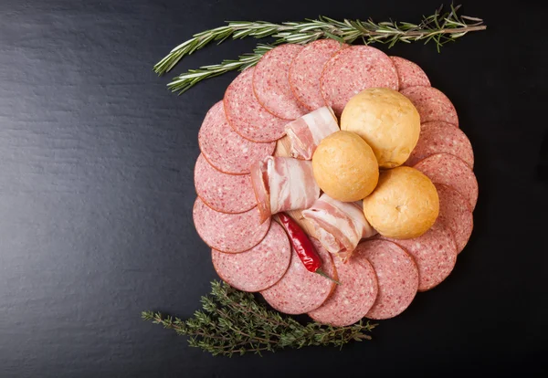 Segmenten van worst en spek op een snijplank met brood broodjes, — Stockfoto