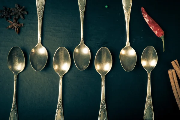 Herbs and spices with old metal spoons on a black background. To — Stock Photo, Image