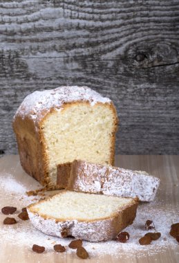 Ahşap masa üzerinde kuru üzüm ve şeker tozu ile pasta. Seçici