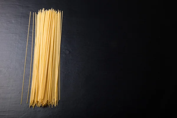 Паста-спагетти на черном фоне. Выборочный фокус. Космос — стоковое фото
