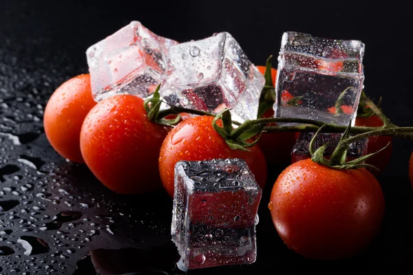 Banch červené cherry rajčat a kostky ledu na černé mokré stole. Se — Stock fotografie
