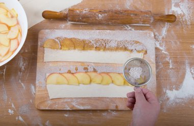 Ateşin üzerinde hamur şeridinde elma dilimleri el sprinkles