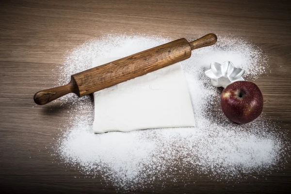 Dough, rolling pin, forms for baking, apple and flour sprinkled — Stock Photo, Image