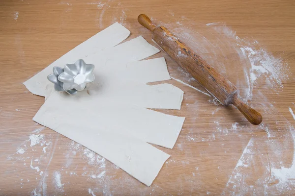 Rayures de pâte, rouleau à pâtisserie et forme de cuisson sur un bois léger — Photo