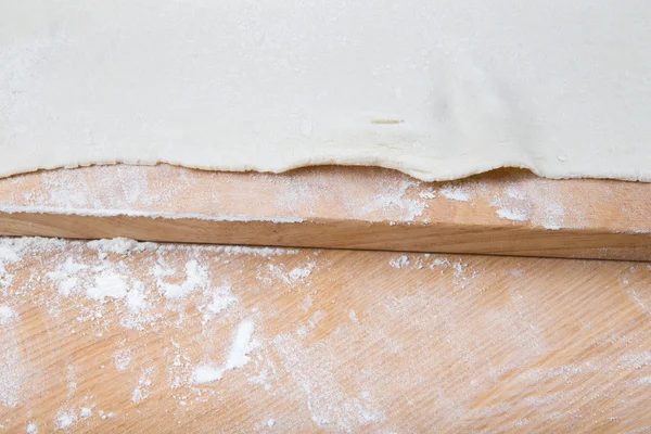Pasta su un tavolo di legno leggero con farina — Foto Stock