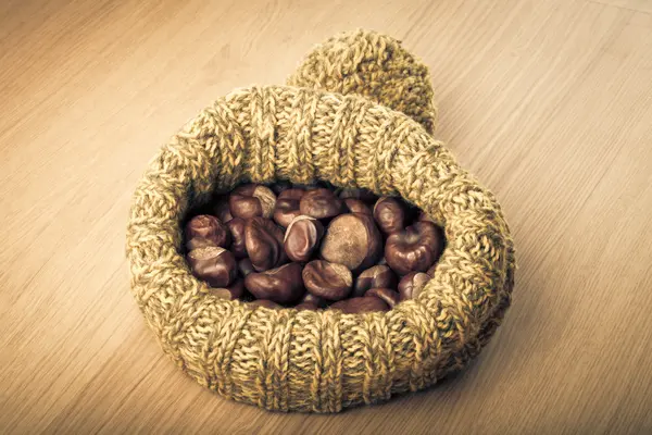 Castañas en un sombrero de punto sobre una mesa de madera clara. Tonificado — Foto de Stock