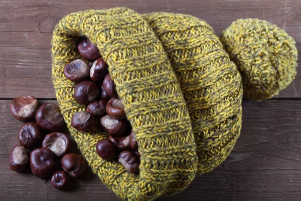 Chestnuts in a knitted hat on a old wooden table — Stock Photo, Image