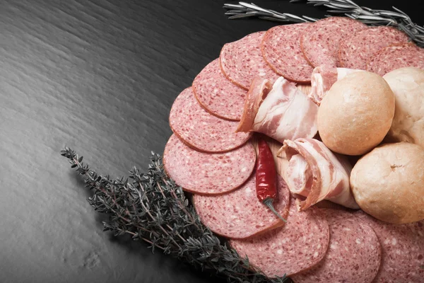 Plato de salchichas en rodajas, pimientos, hierbas y panecillos franceses o — Foto de Stock