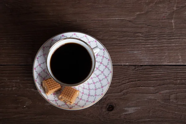 Top view to porcelain cup of coffee with toffee on old wooden ta — Stock Photo, Image