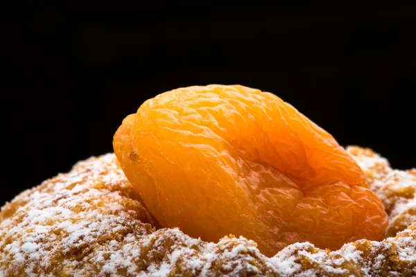 Сухой абрикос на торте с сахарным порошком на черной спине — стоковое фото