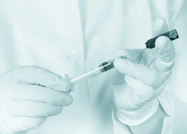 Hands in gloves filling medicine from ampule into syringe agains — Stock Photo, Image