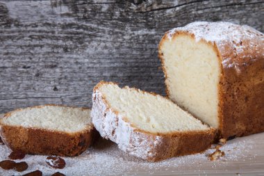 Ahşap masa üzerinde kuru üzüm ve şeker tozu ile pasta. Seçici