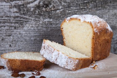 Ahşap masa üzerinde kuru üzüm ve şeker tozu ile pasta. Seçici