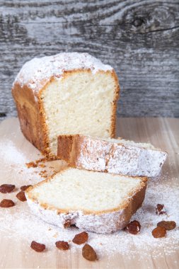 Ahşap masa üzerinde kuru üzüm ve şeker tozu ile pasta. Seçici