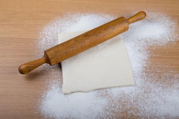 Rolling pin, dough and baking form on a light wooden table with — Stock Photo, Image