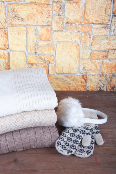 Mittens, fur headphones and stack of knitting clothes on wooden — Stock Photo, Image