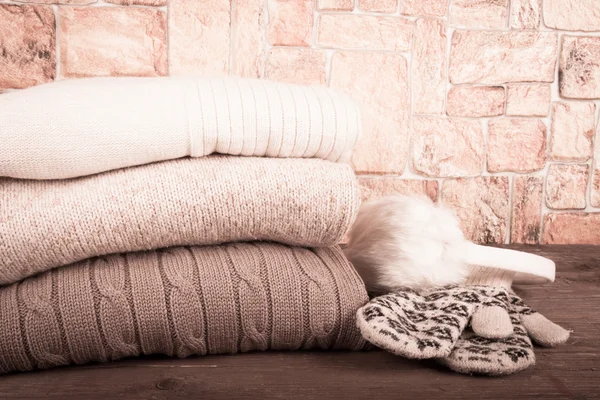 Mittens, fur headphones and stack of knitting clothes on wooden — Stockfoto