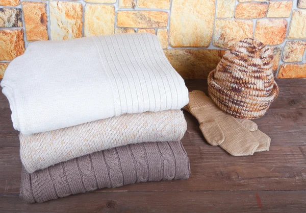 Pilha de roupas de tricô, chapéu e luvas em oppos de mesa de madeira — Fotografia de Stock