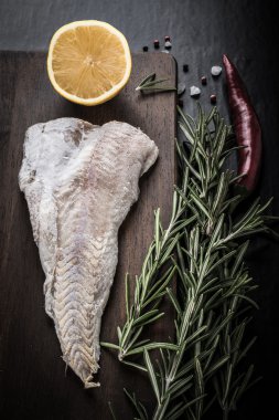 Fish filet, rosemary, red chili pepper, half a lemon and sea sal