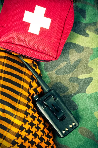 First aid kit and portable radio on a fabric with camouflage pat