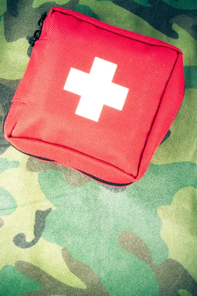First aid kit on a fabric with camouflage pattern. Toned — Stock Photo, Image