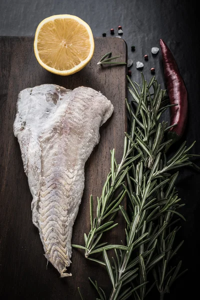 Fish filet, rosemary, red chili pepper, half a lemon and sea sal — Zdjęcie stockowe