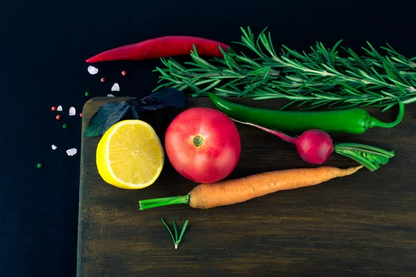 Vegetables and herbs with sea salt on brown cutting board on a b — Stock Photo, Image