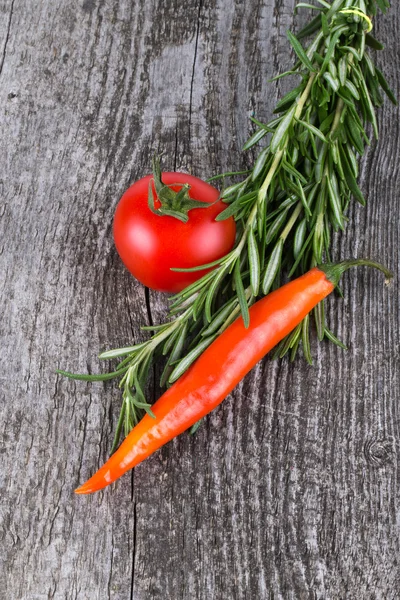 Snítka rozmarýnu, rajče a paprika na starý dřevěný stůl. Pozadí — Stock fotografie