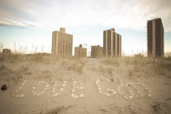 Felirat szeretet Isten tengeri kagylókból a homok a tengerparton. Keleti — Stock Fotó