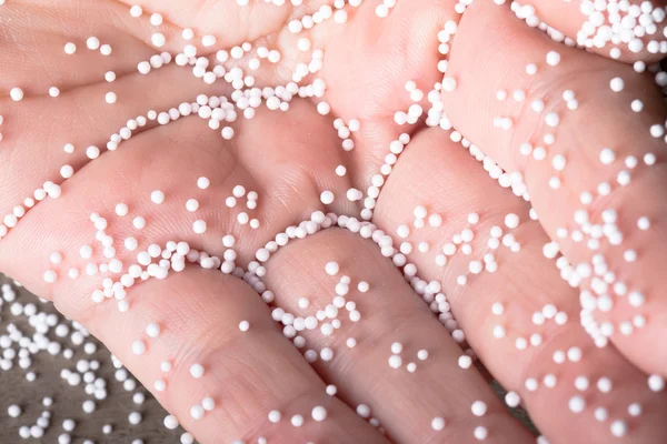 stock image Human hand with pieces of foam plastic like snow balls on the ba