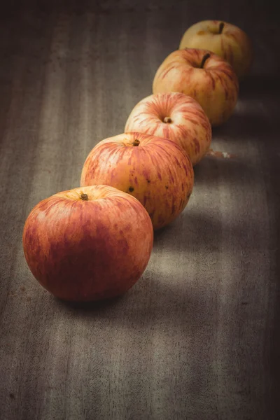 Řádek žluto červená sezónní jablek na pozadí staré desky — Stock fotografie