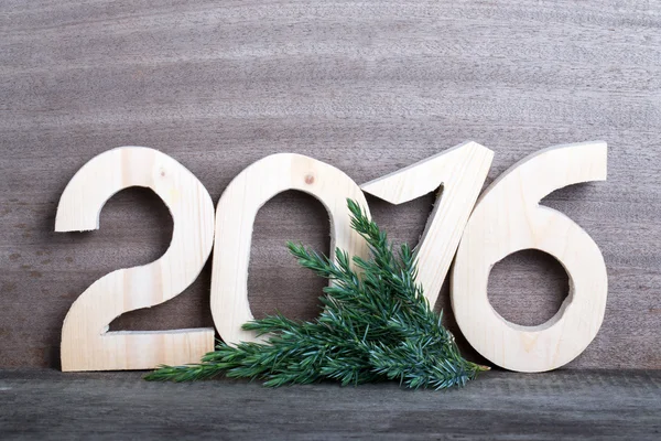 Wooden figures 2016 and branch of the Christmas tree on gray woo — Stock Photo, Image