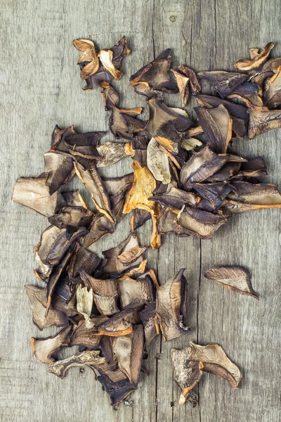 Trozos de champiñones porcini secos sobre tabla de madera gris vieja. Tono — Foto de Stock