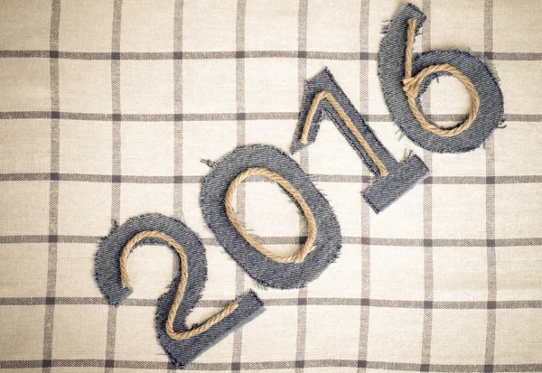 Веревка и джинсовые цифры 2016 года на клетчатом фоне ткани. Тон — стоковое фото