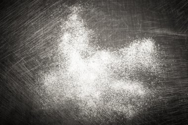 White wheat flour is scattered on an old worn cutting board. Bac