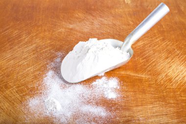 Scoop with white wheat flour on an old rugged cutting board