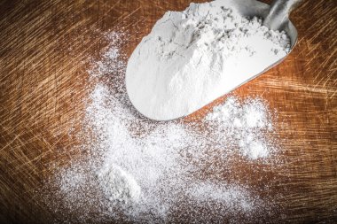 Scoop with white wheat flour on an old rugged cutting board. Ton