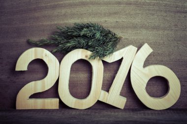 Light wooden figures 2016 and branch of the Christmas tree on gr