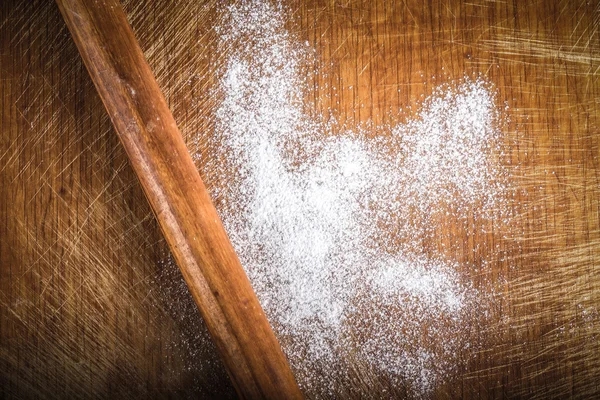 White wheat flour is scattered on an old worn cutting board. Bac — ストック写真