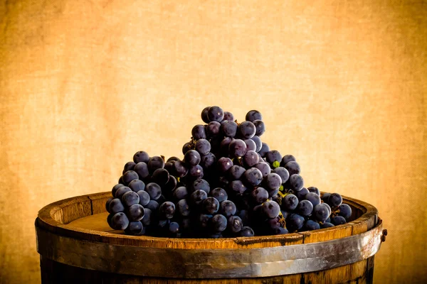 Barrel and ripe grapes of wine on burlap background. Toned — Stock Photo, Image