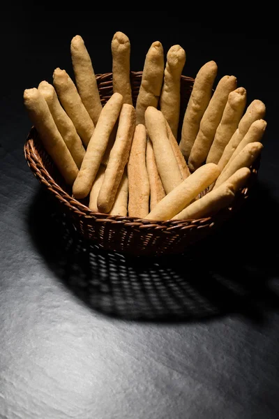 Bastoncini di formaggio appena sfornati in un cesto di legno di vimini sulla linguetta nera — Foto Stock