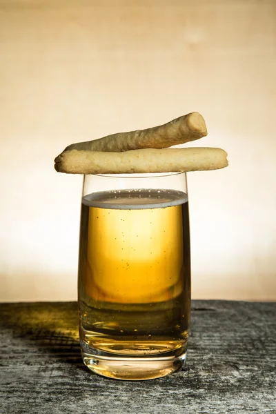 Cheese pastry and glass of light beer on light grey table. Selec — Stock Photo, Image