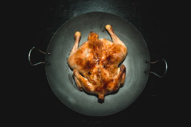 Siyah ahşap bir masa üzerinde bir Pan kızarmış tavuk. Tonda