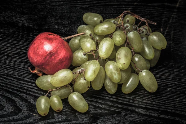 Raisin frais juteux mûr et grenade sur une table ou une planche noire — Photo