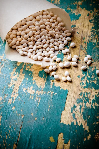 Bílé fazole v papírový sáček na starý dřevěný stůl. Ingredience pro — Stock fotografie
