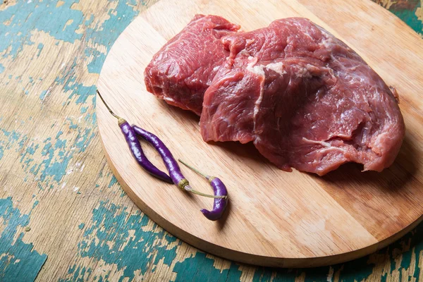 Carne fresca cruda sobre tabla de cortar ligera sobre una mesa de madera vieja. En — Foto de Stock