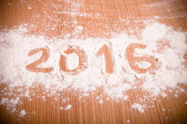 Figures 2016 on flour spilling on wooden background. Selective f — Stock Photo, Image